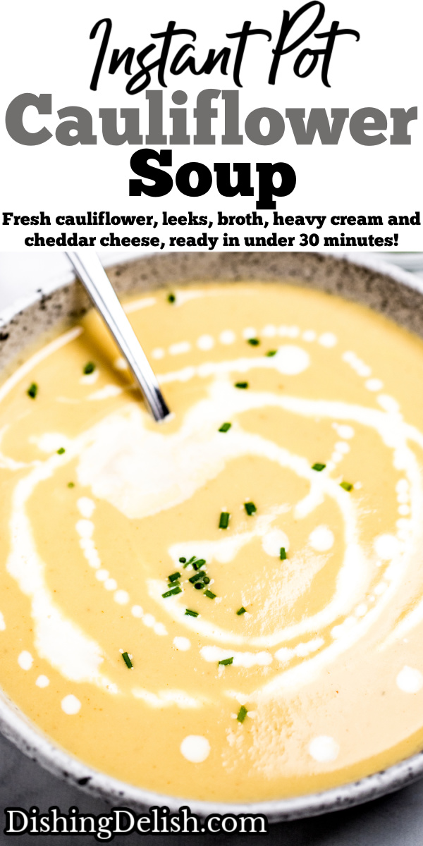 A bowl of cauliflower soup on a table, with cream drizzled on top and fresh chives.