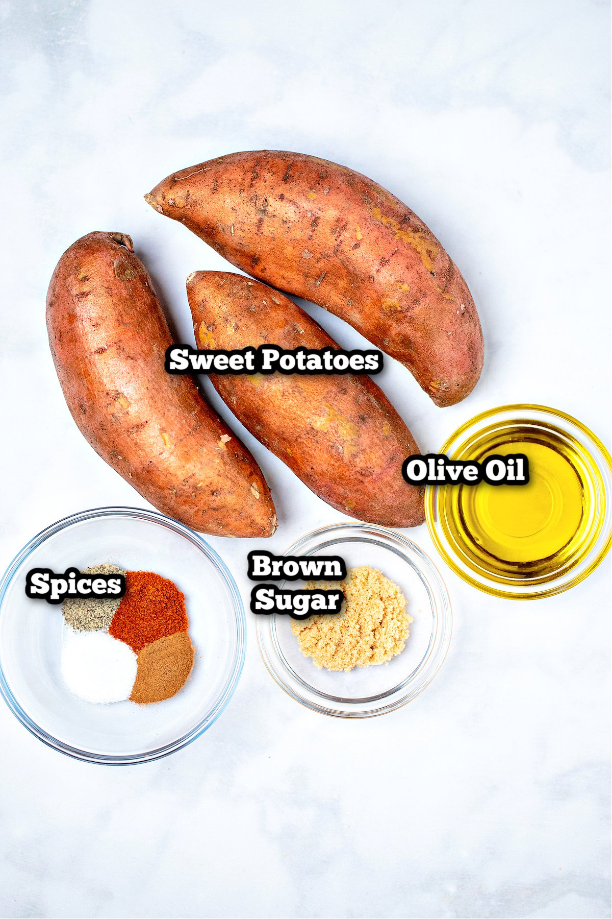 Individual ingredients for baked sweet potato slices on a marble table.