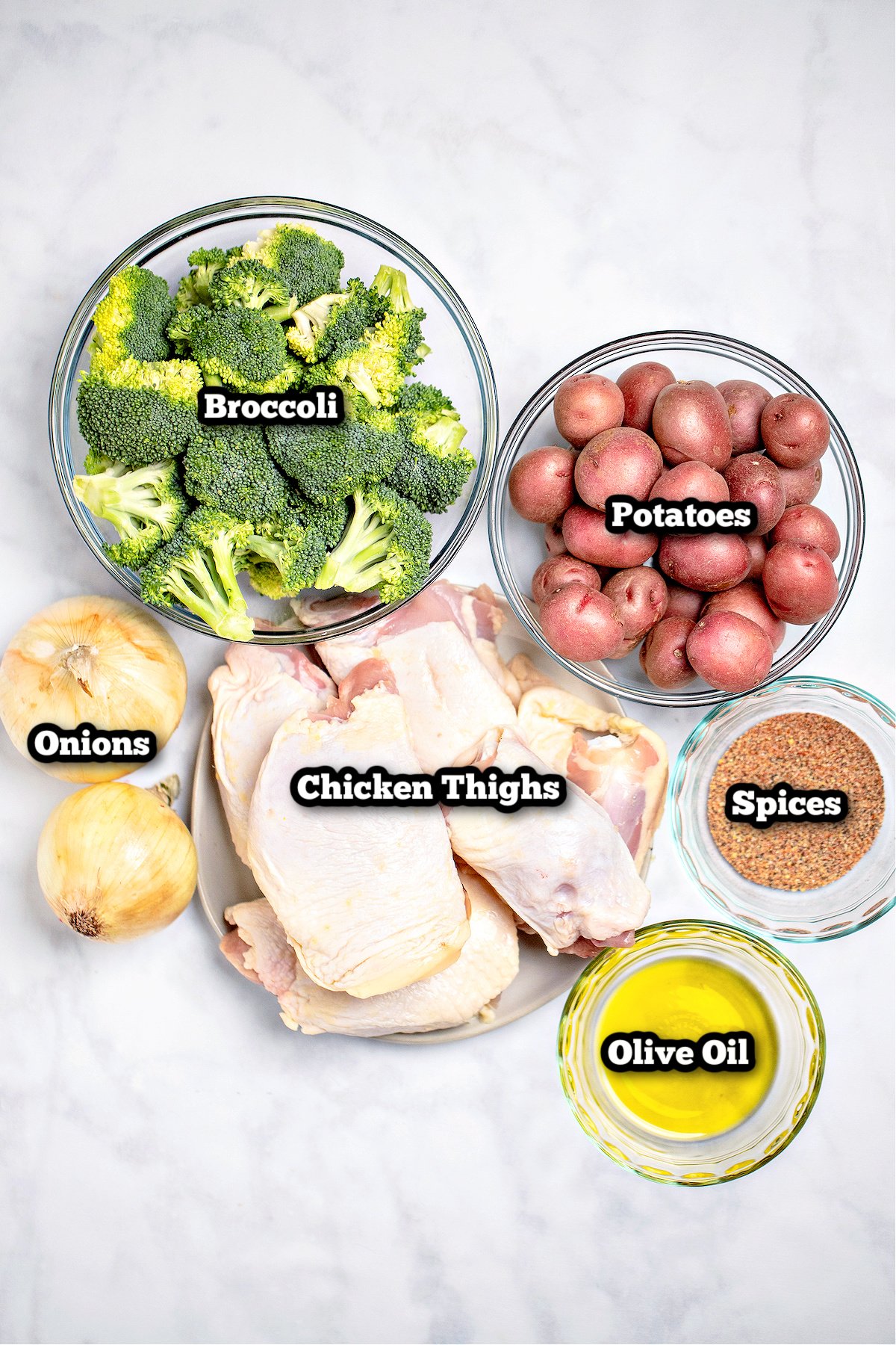 Individual ingredients for sheet pan chicken thighs on a table.
