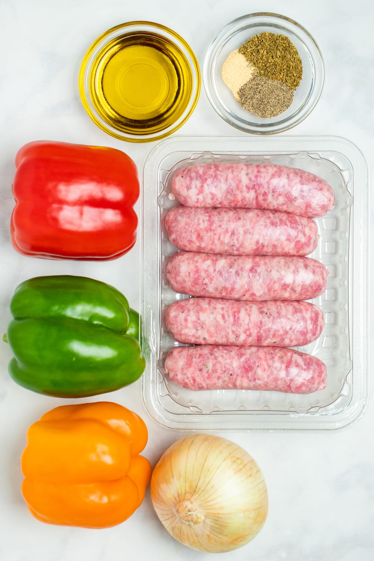 Individual ingredients for sausage and peppers on a table. 