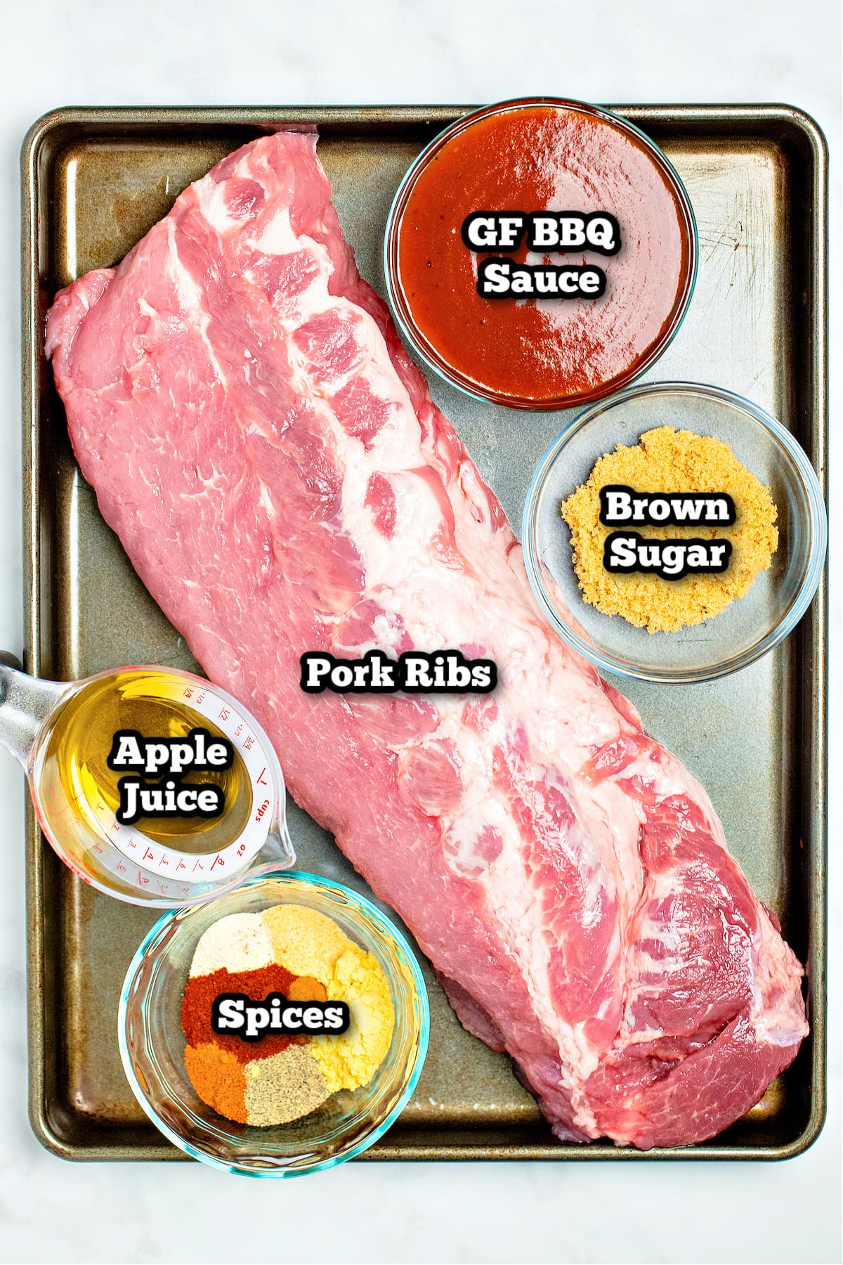 Individual ingredients for instant pot pork ribs on a baking sheet on a table.