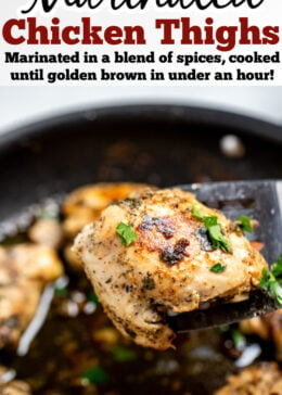 Pinterest pin with Greek marinated chicken thighs in a skillet topped with fresh parsley, with a spatula lifting a piece of chicken up.