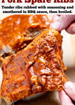 Pinterest pin with two hands lifting up a section of pork spare ribs smothered in bbq sauce from a piece of parchment paper on a cutting board, with more sections of ribs in the background.