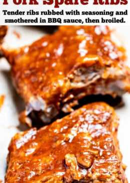 Pinterest pin with a section of pork spare ribs smothered in bbq sauce on a piece of parchment paper on a cutting board, with more sections of ribs in the background.