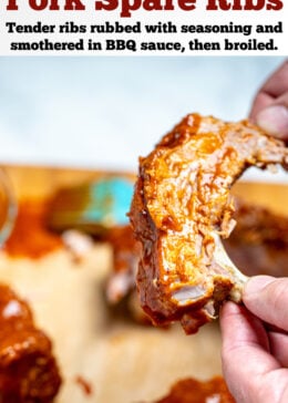 Pinterest pin with two hands holding a spare rib smothered in bbq sauce above a cutting board with parchment paper and more ribs sections, and a bbq sauce brush.