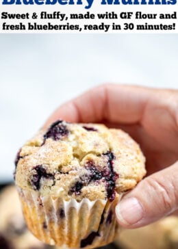 Pinterest pin with a hand holding a gluten free blueberry muffin above the tray of muffins.
