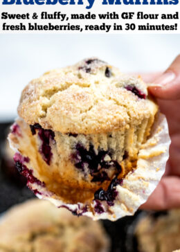 Pinterest pin with a hand holding a gluten free blueberry muffin above the tray of muffins, with half of the paper liner taken off.