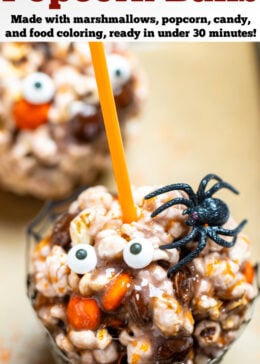 Pinterest pin with a halloween popcorn ball in a cupcake holder that looks like a spider web, with a spider on top of the ball, sitting on a sheet pan.