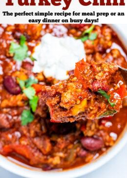 Pinterest pin with a spoon scooping turkey chili out of a bowl of chili topped with sour cream.