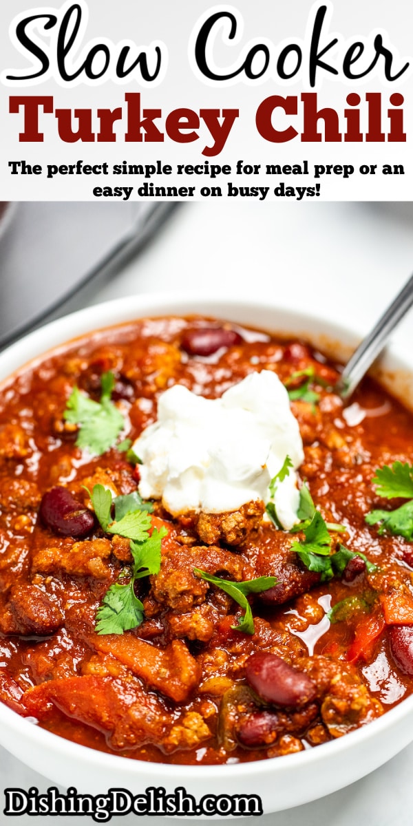 Pinterest pin with a bowl of turkey chili with a spoon topped with sour cream and fresh cilantro.