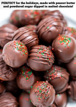 Pinterest pin with chocolate covered peanut butter balls piled on a plate topped with drizzled chocolate and sprinkles on a table.