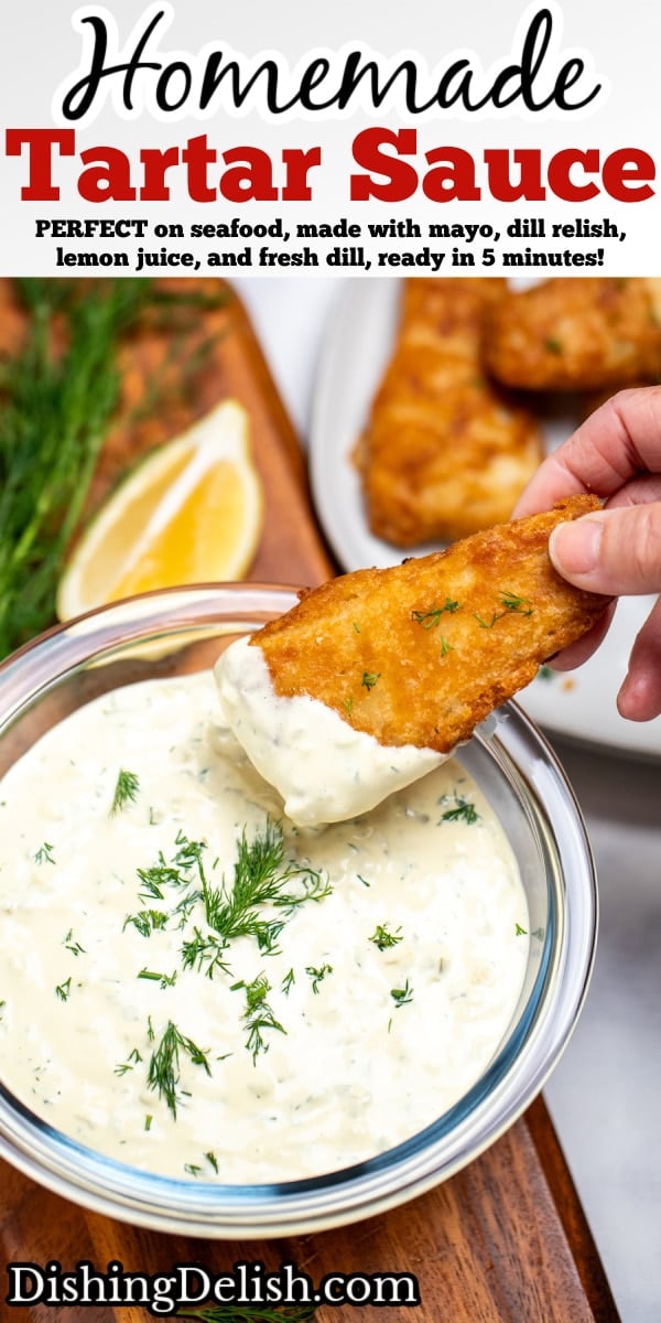 Pinterest pin with a bowl of homemade tartar sauce on a cutting board, topped with fresh dill and a hand dipping a fish stick into the sauce, with a lemon wedge in the background.
