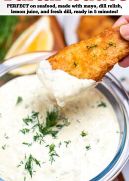 Pinterest pin with a bowl of homemade tartar sauce on a cutting board, topped with fresh dill and a hand dipping a fish stick into the sauce, with a lemon wedge in the background.