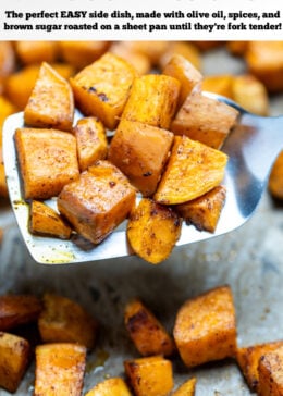 Pinterest pin with roasted sweet potato cubes on a sheet pan with parchment paper, being lifted up by a spatula.