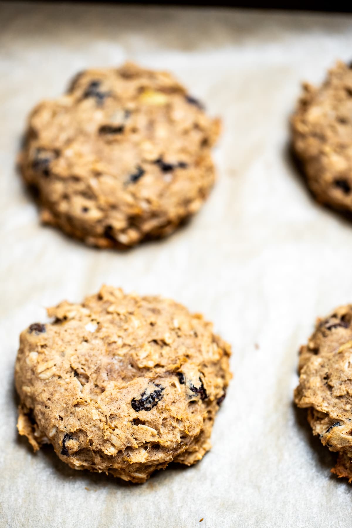 Oatmeal breakfast cookies sitting on a sheet pan with parchment paper.