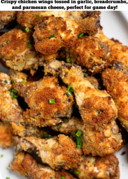 Pinterest pin with a plate with garlic parmesan wings in a pile topped with chives and next to a bowl of ranch and celery.