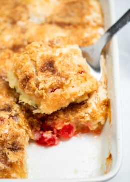 A spatula taking a piece of pineapple dump cake out of the baking dish.