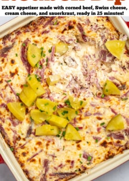 Pinterest pin with reuben dip topped with pickles in a baking dish on a table.