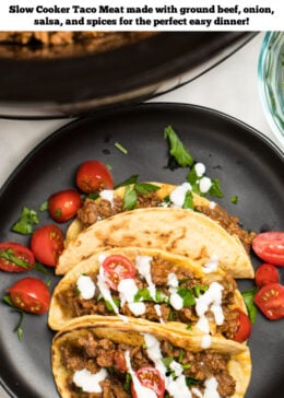 Pinterest pin with a plate of three beef tacos with cherry tomatoes and drizzled with sour cream, in front of a slow cooker full of slow cooker taco meat.
