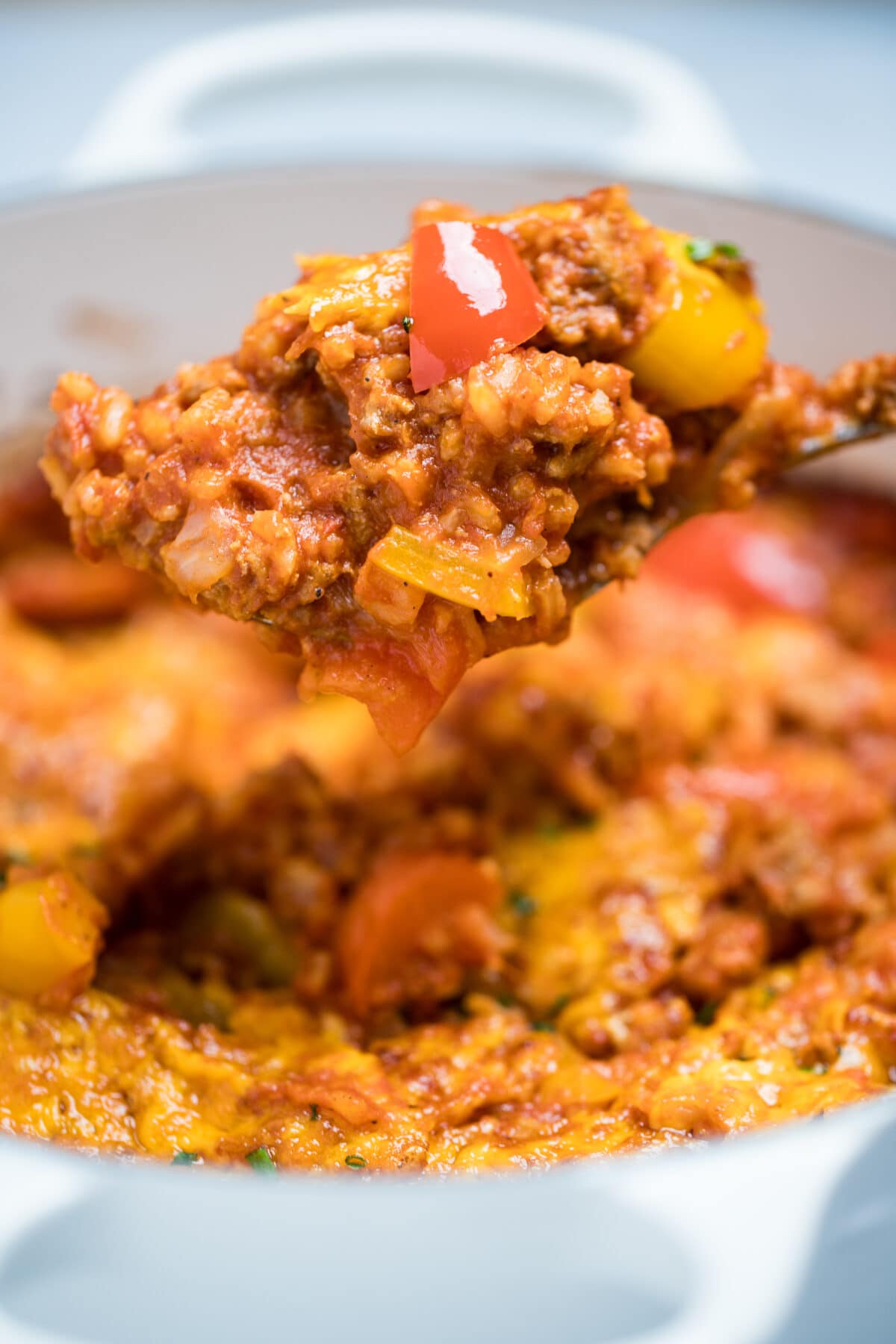 Stuffed pepper casserole in a dutch oven with a spoon scooping some casserole up.