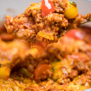 Stuffed pepper casserole in a dutch oven with a spoon scooping some casserole up.