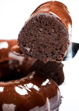 A piece of cake being lifted up from the chocolate brownie bundt cake.