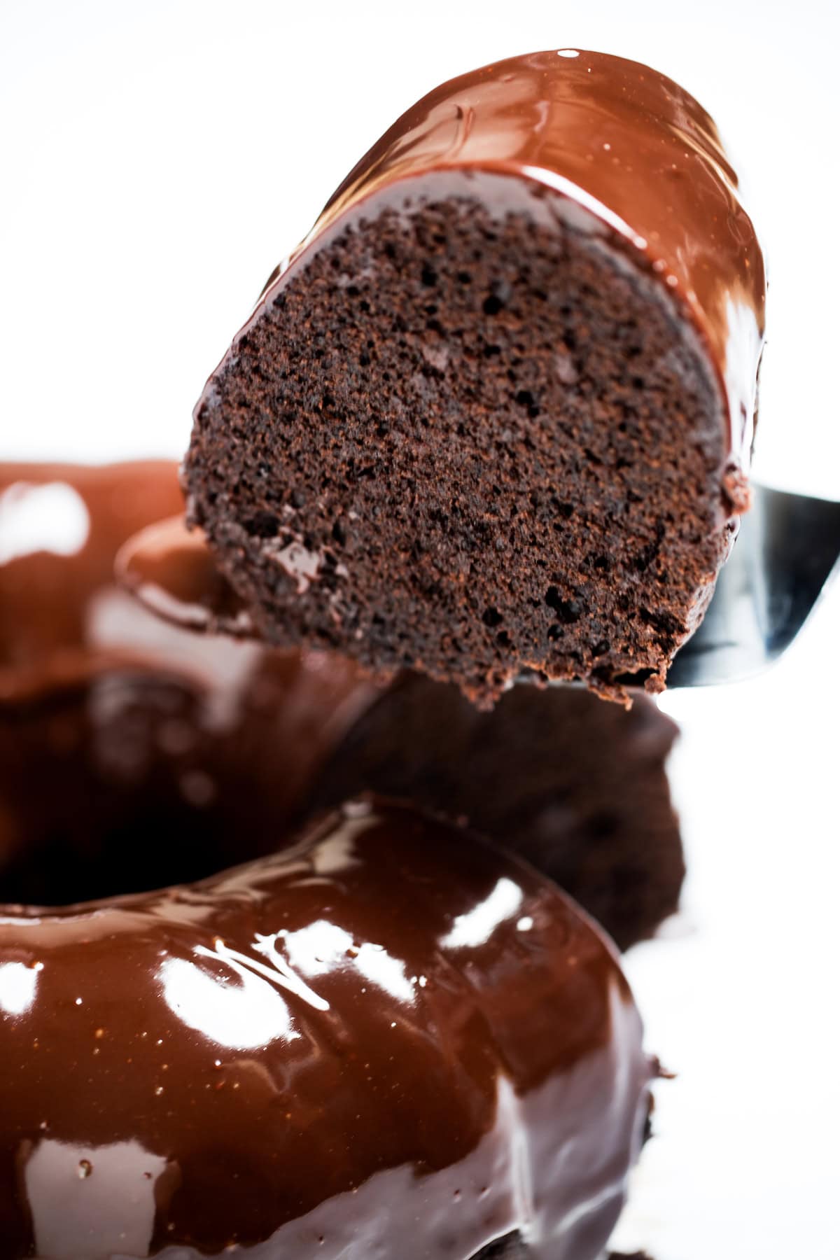 A piece of cake being lifted up from the chocolate brownie bundt cake.