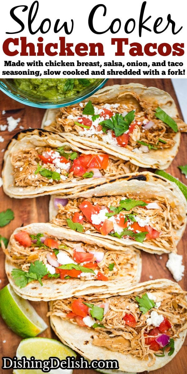 Pinterest pin with a cutting board with five slow cooker chicken tacos in corn tortillas topped with tomato, red onion, queso fresco, and cilantro, next to a bowl of guacamole and lime wedges.