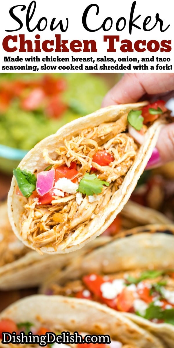 Pinterest pin with a hand holding a taco in a corn tortilla topped with tomato, red onion, queso fresco, and cilantro, above a cutting board with more tacos and a bowl of guacamole.