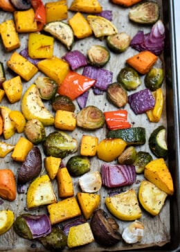 Roasted vegetables on top of parchment paper on a sheet pan, just out of the oven.