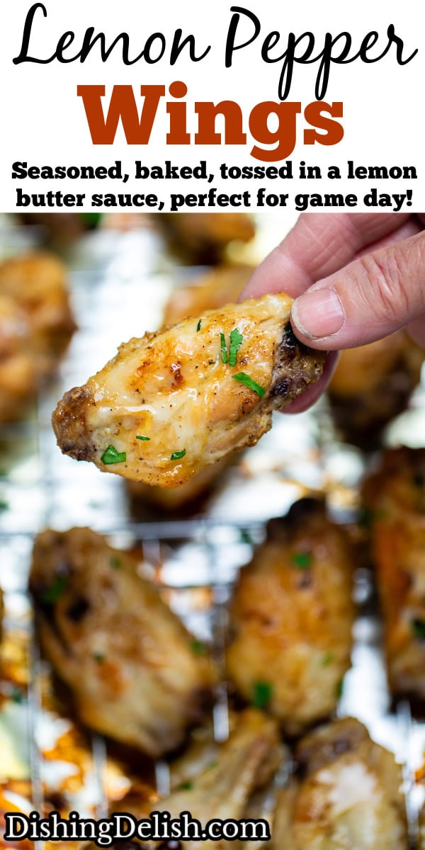 Pinterest pin with a hand holding a chicken wing above a baking rack of cooked chicken wings topped with fresh parsley.