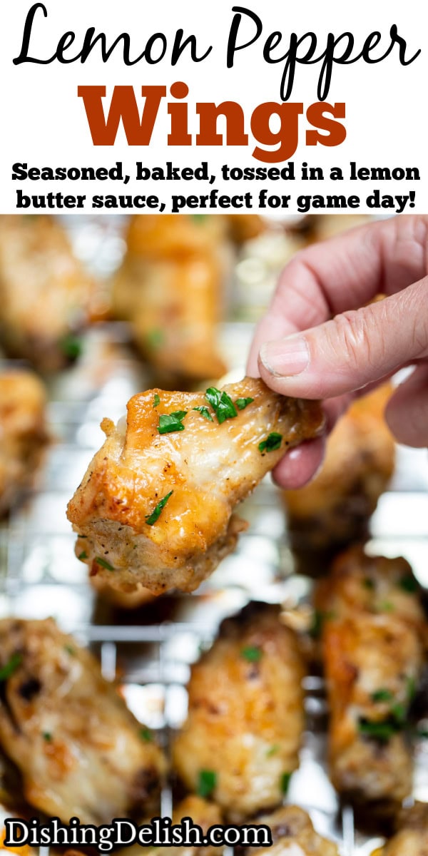 Pinterest pin with a hand holding a chicken wing above a baking rack of cooked chicken wings topped with fresh parsley.