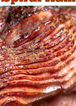 Pinterest pin with a close up of a spiral ham with the slices slightly separated from each other, on a sheet pan.