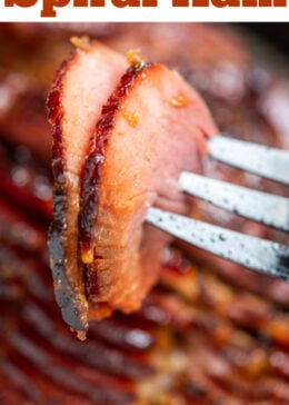 Pinterest pin with a fork lifting up two pieces of ham, above the rest of the spiral ham.