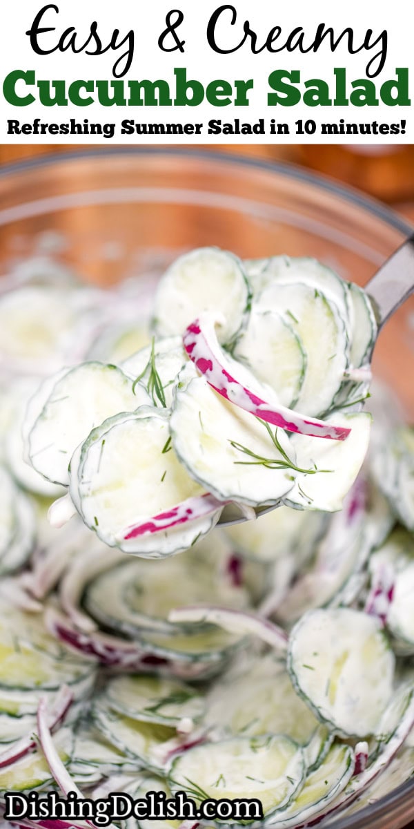 Pinterest pin with a glass mixing bowl on a cutting board full of creamy cucumber salad with red onions topped with fresh dill, with a spoon lifting some up.