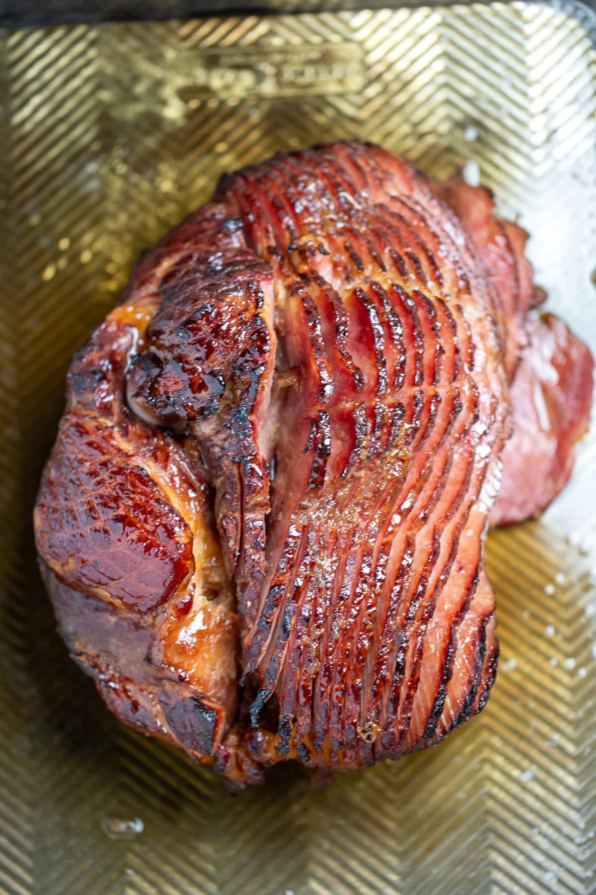 A spiral ham resting on a sheet pan right after being broiled, with the pieces slightly separated from each other.