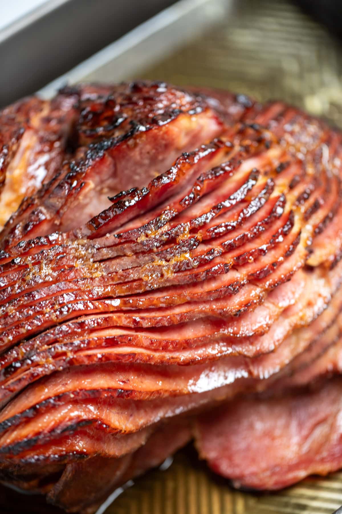 A spiral ham resting on a sheet pan right after being broiled, with the pieces slightly separated from each other.