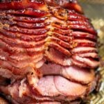 A spiral ham resting on a sheet pan right after being broiled, with the pieces slightly separated from each other.