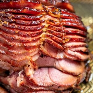 A spiral ham resting on a sheet pan right after being broiled, with the pieces slightly separated from each other.