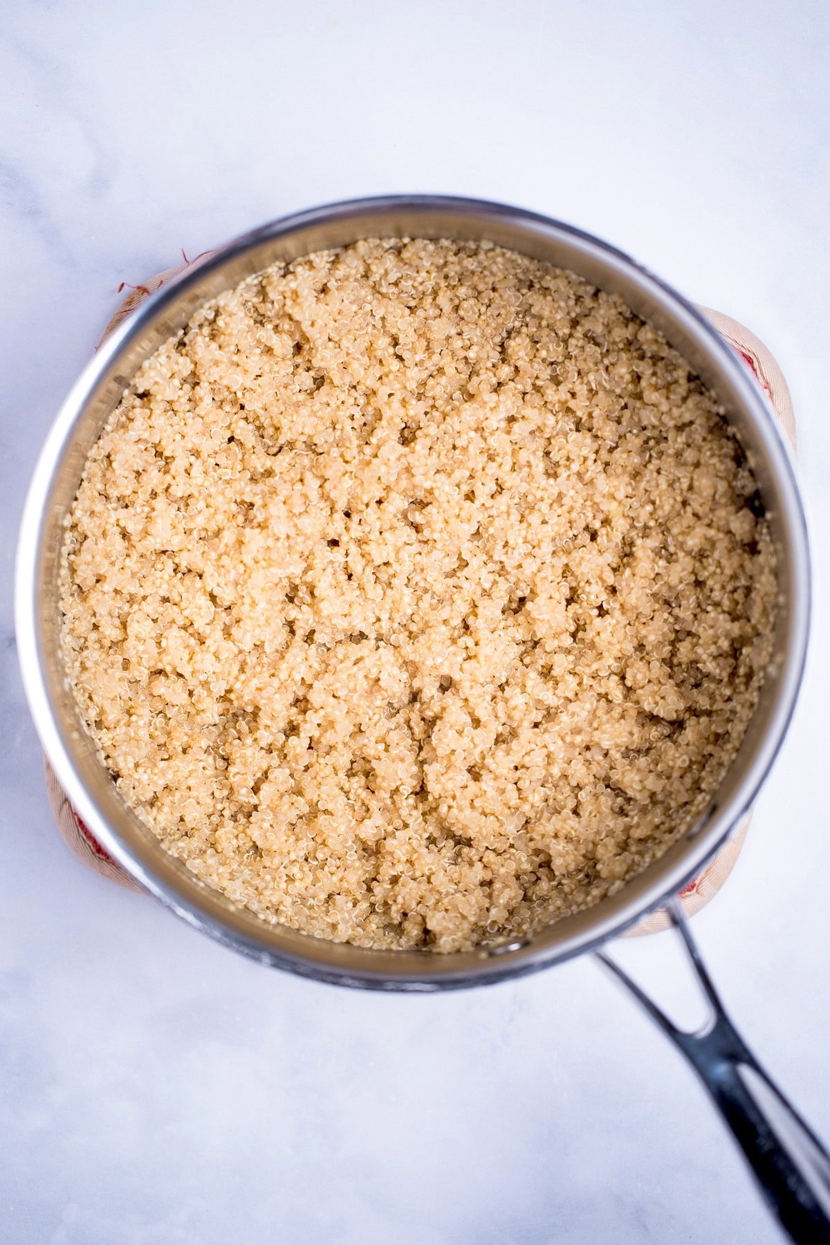 A saucepan on a table full of cooked quinoa.