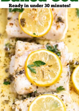 Pinterest pin with a baking dish, with four cooked cod fillets, topped with lemon slices and fresh parsley, and in a lemon butter sauce.