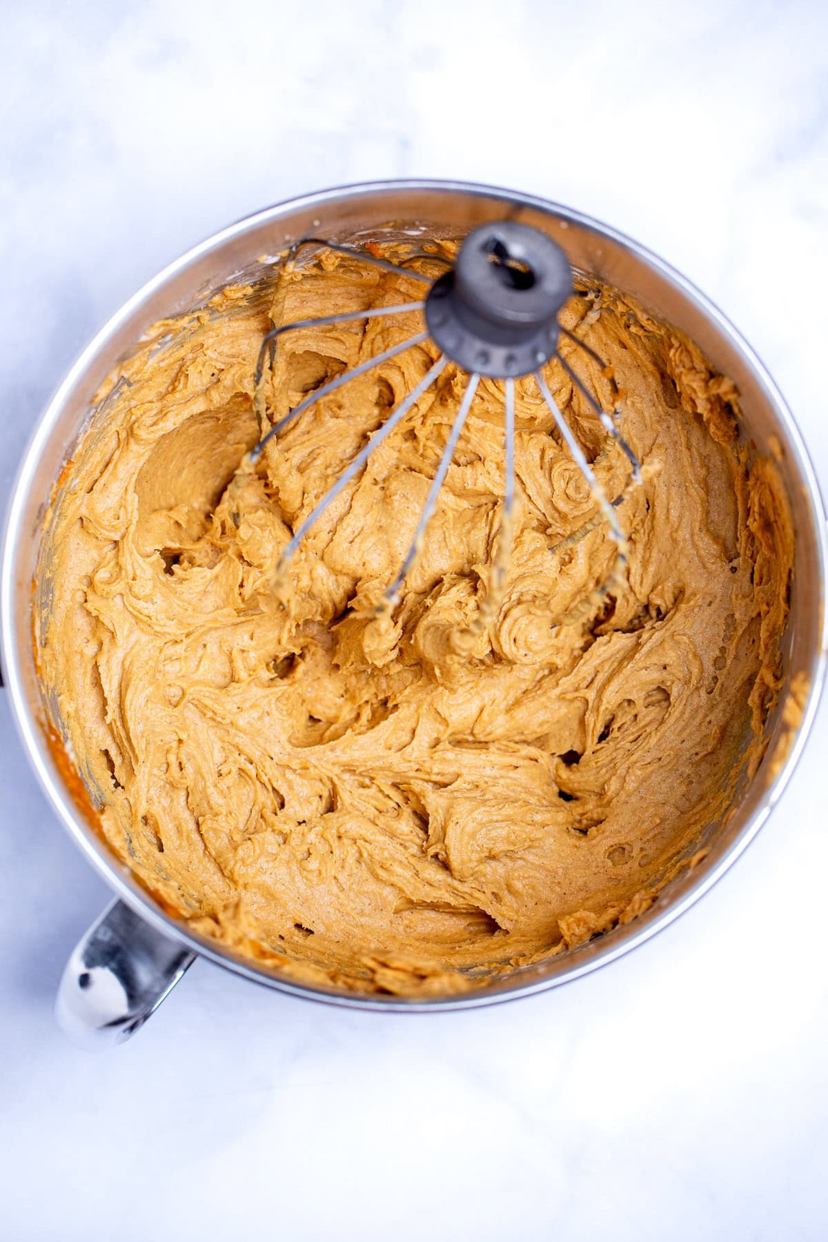 A mixing bowl from a stand mixer with coffee cake batter and a whisk attachment sitting in the batter.