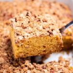 A spatula lifting a piece of pumpkin coffee cake out of the baking dish.