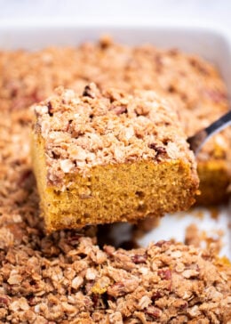 A spatula lifting a piece of pumpkin coffee cake out of the baking dish.