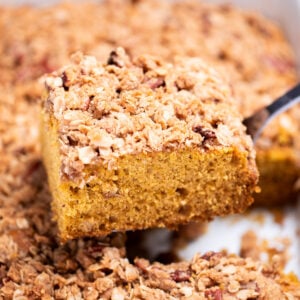 A spatula lifting a piece of pumpkin coffee cake out of the baking dish.