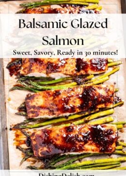 Pinterest pin with a sheet pan lined with parchment paper with four salmon fillets resting on top of asparagus, topped with a balsamic reduction.