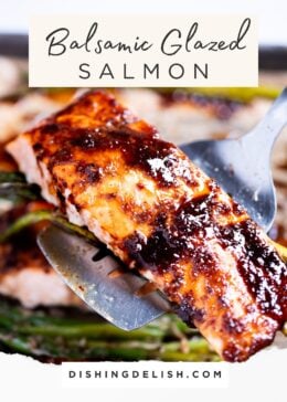 Pinterest pin with a spatula holding a balsamic glazed salmon fillet over a sheet pan with salmon and asparagus.