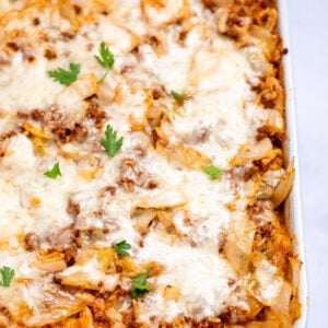 A casserole dish with Cabbage Roll Casserole topped with mozzarella cheese and fresh parsley before being served.