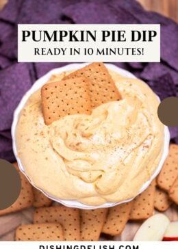 Pinterest pin of a bowl full of pumpkin pie dip resting on a cutting board, surrounded by gluten free graham crackers, apple slices, and blue corn chips.