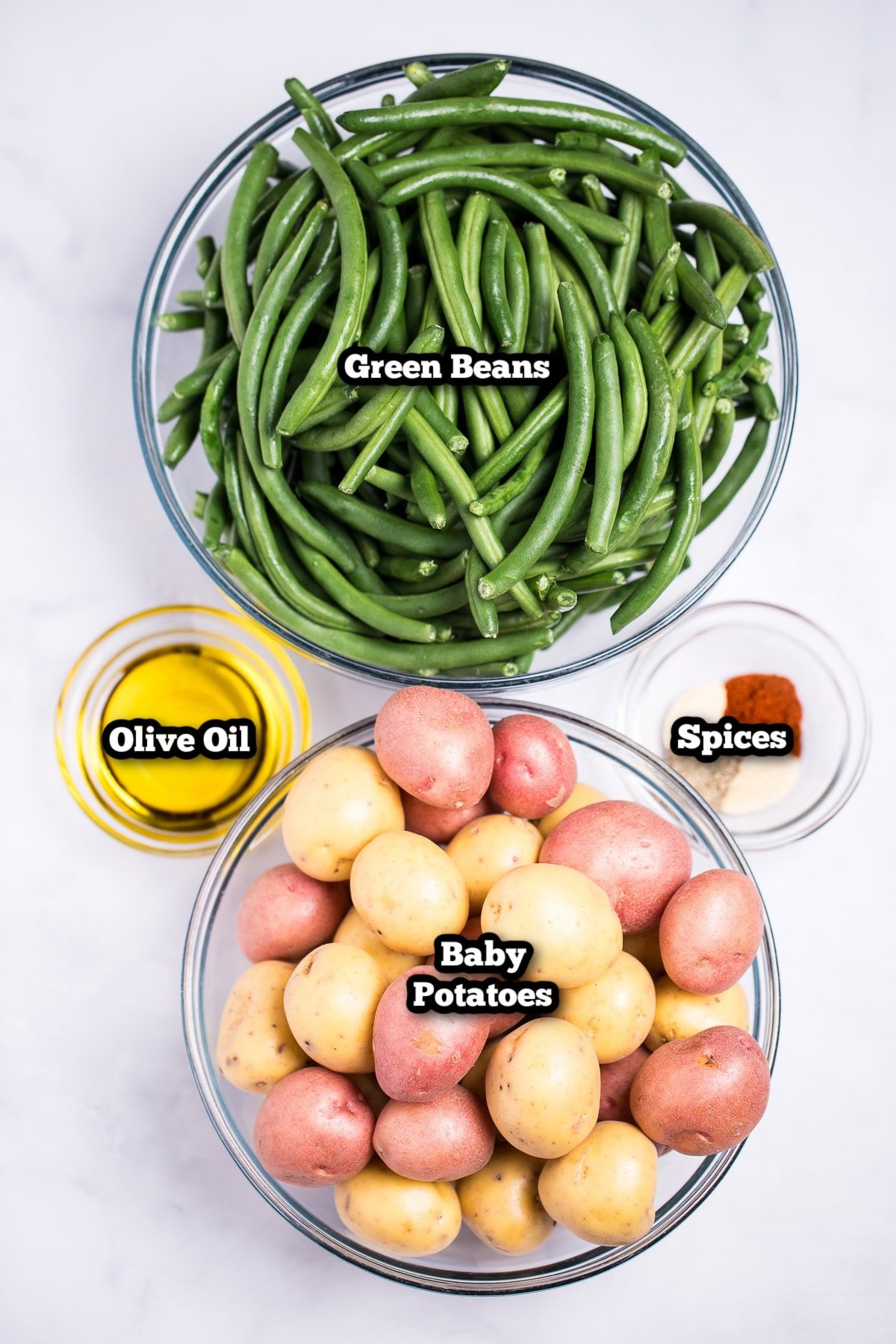 Individual ingredients for roasted potatoes and green beans on a table.